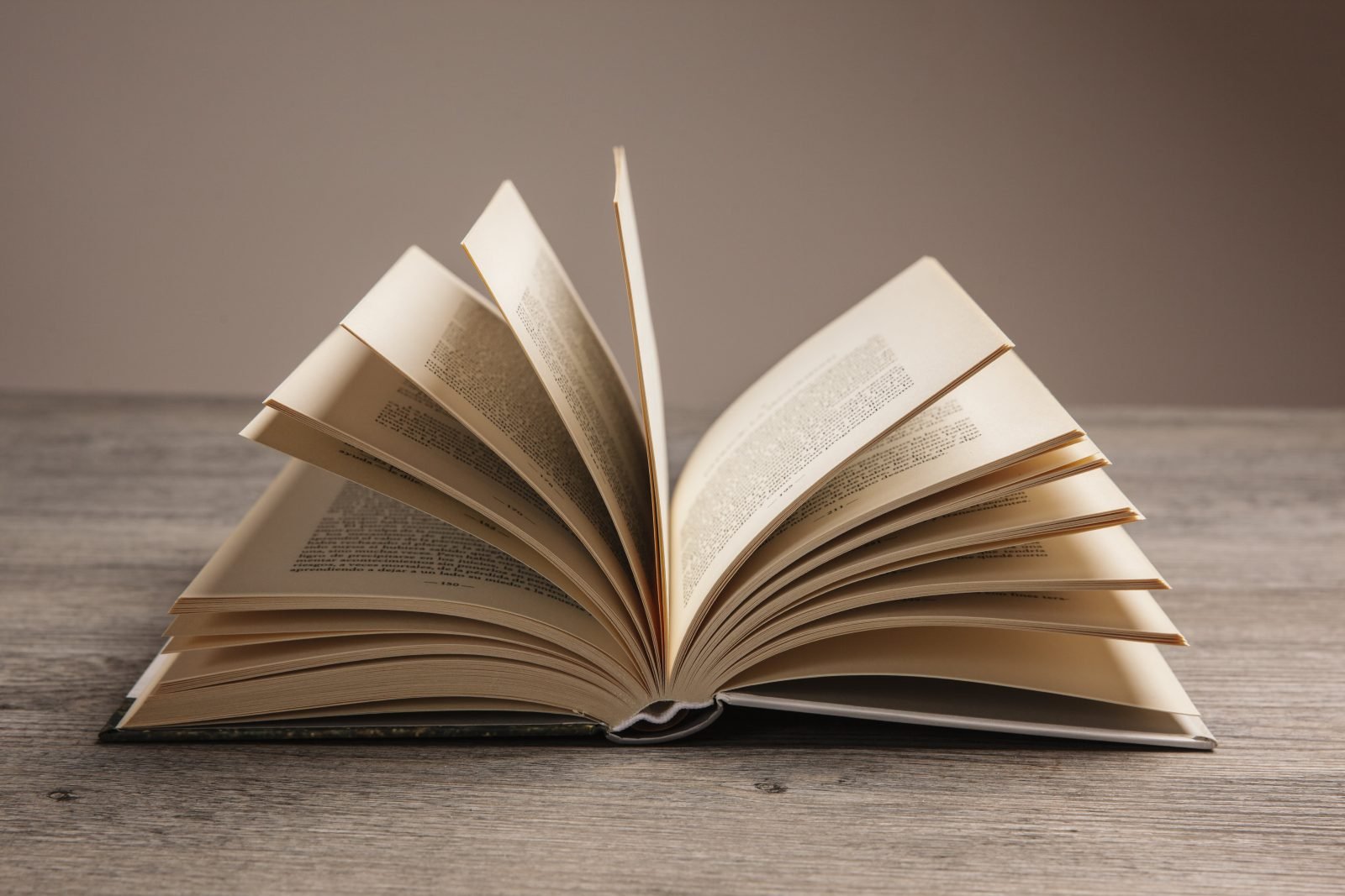 An open book resting on a wooden table, inviting readers to explore its pages and delve into the world of knowledge.